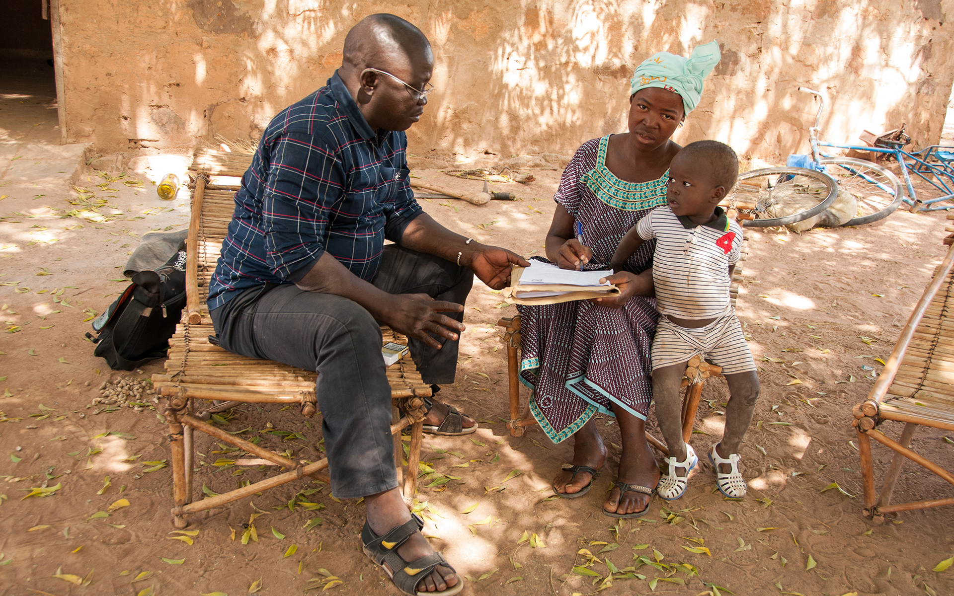 Anè, a women taking part in a Tree Aid enterprise project in Mali, with her child talking to a Tree Aid staff member.
