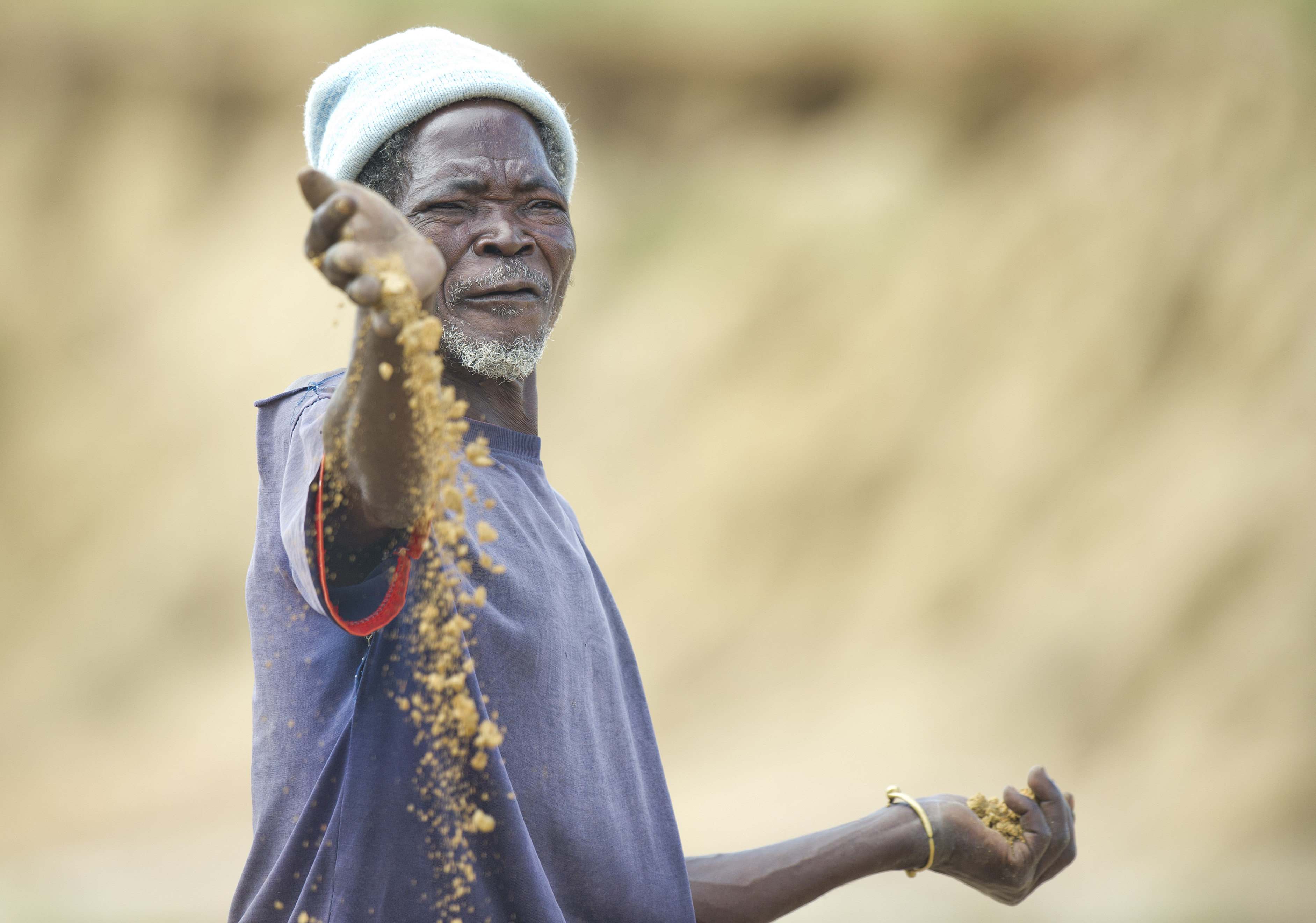 A man in the Sahel, holding sand in his hand 