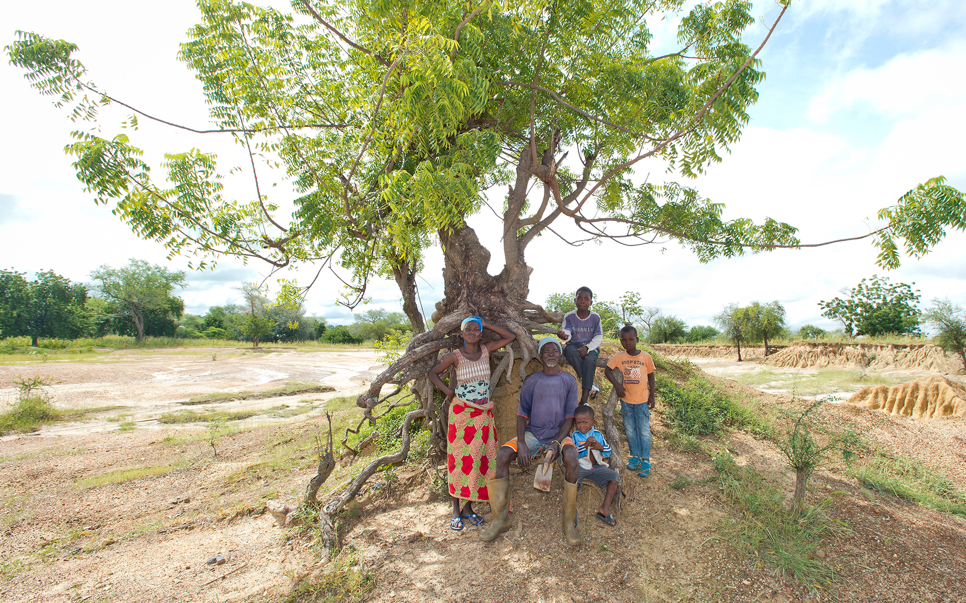 Mbole, a man in Ghana who is participating in a Tree Aid project, is sitting on degraded land with his family. Photo credit: Rowan Griffiths, Daily Mirror