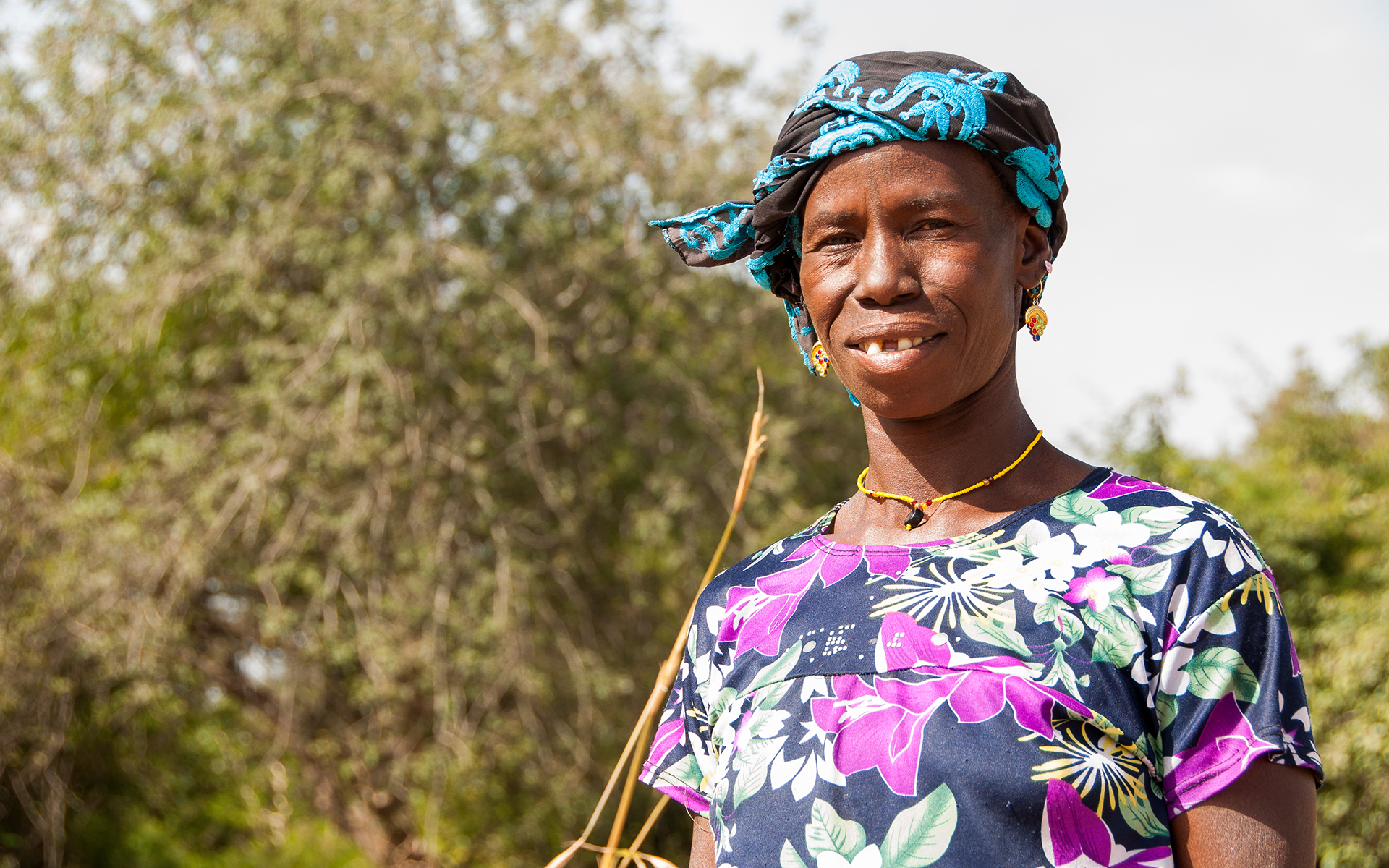 A women in Koulikoro smiling in front of trees.