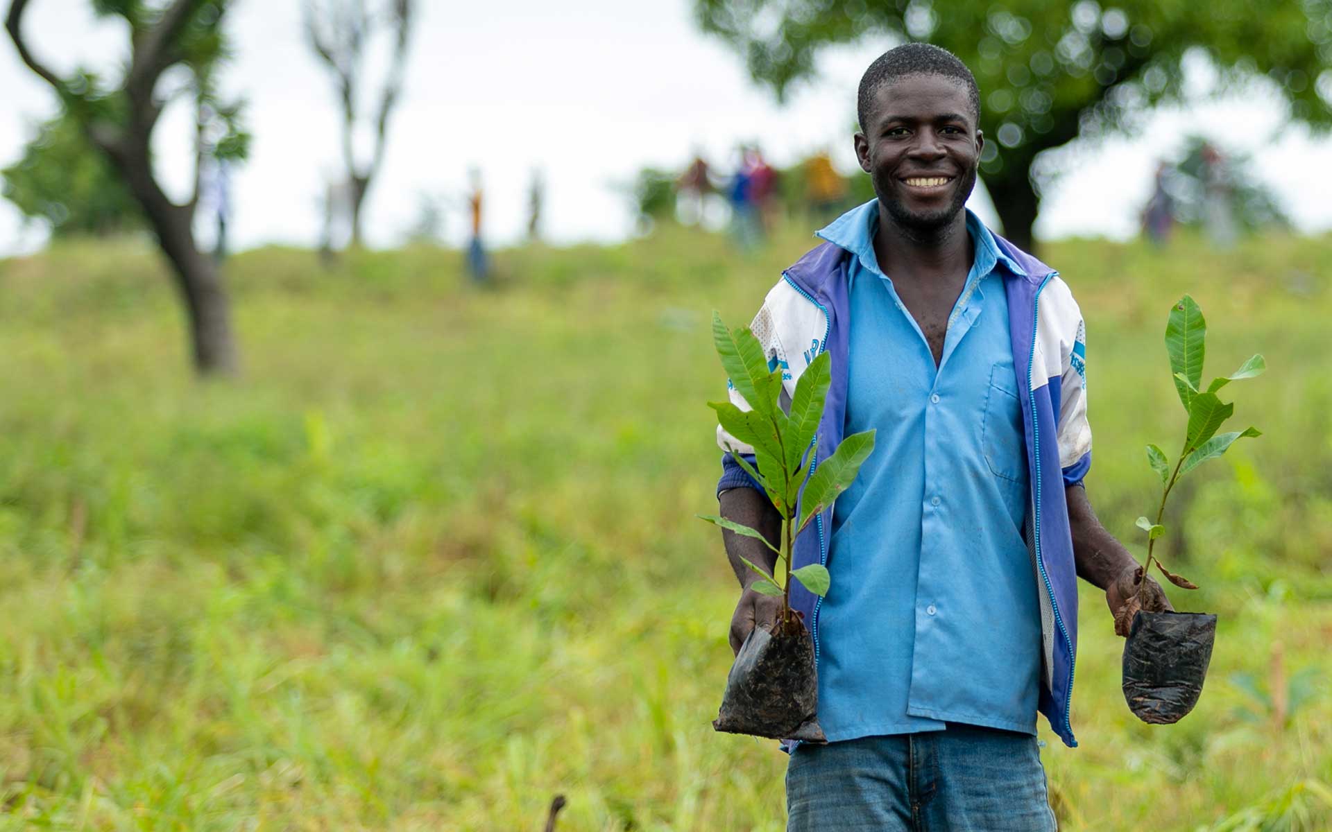 Francis, a man we are working with in Ghana, holding a tree sapling in each hand which he will plant in the community. 