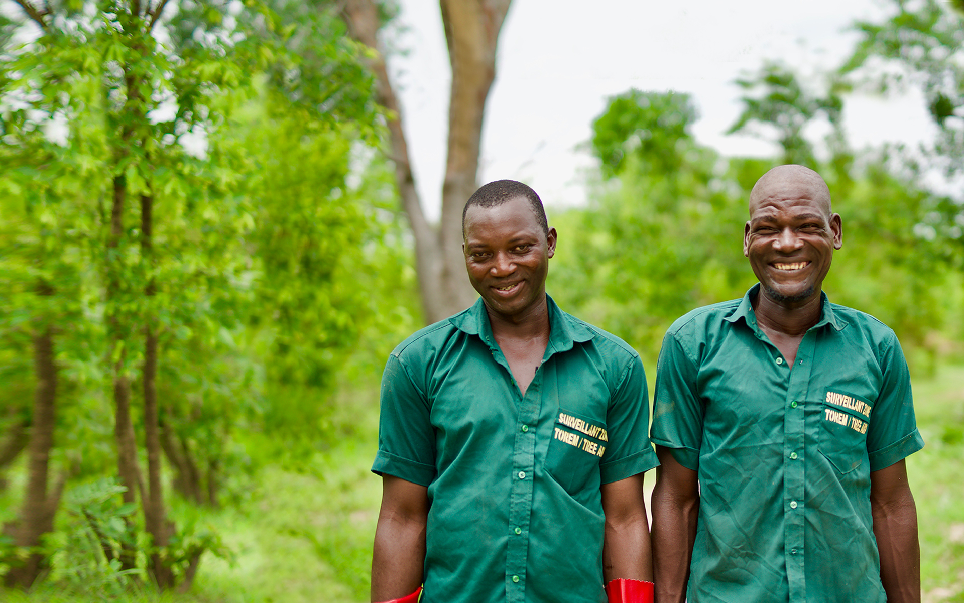 Two forest guards smiling in front of a forest.