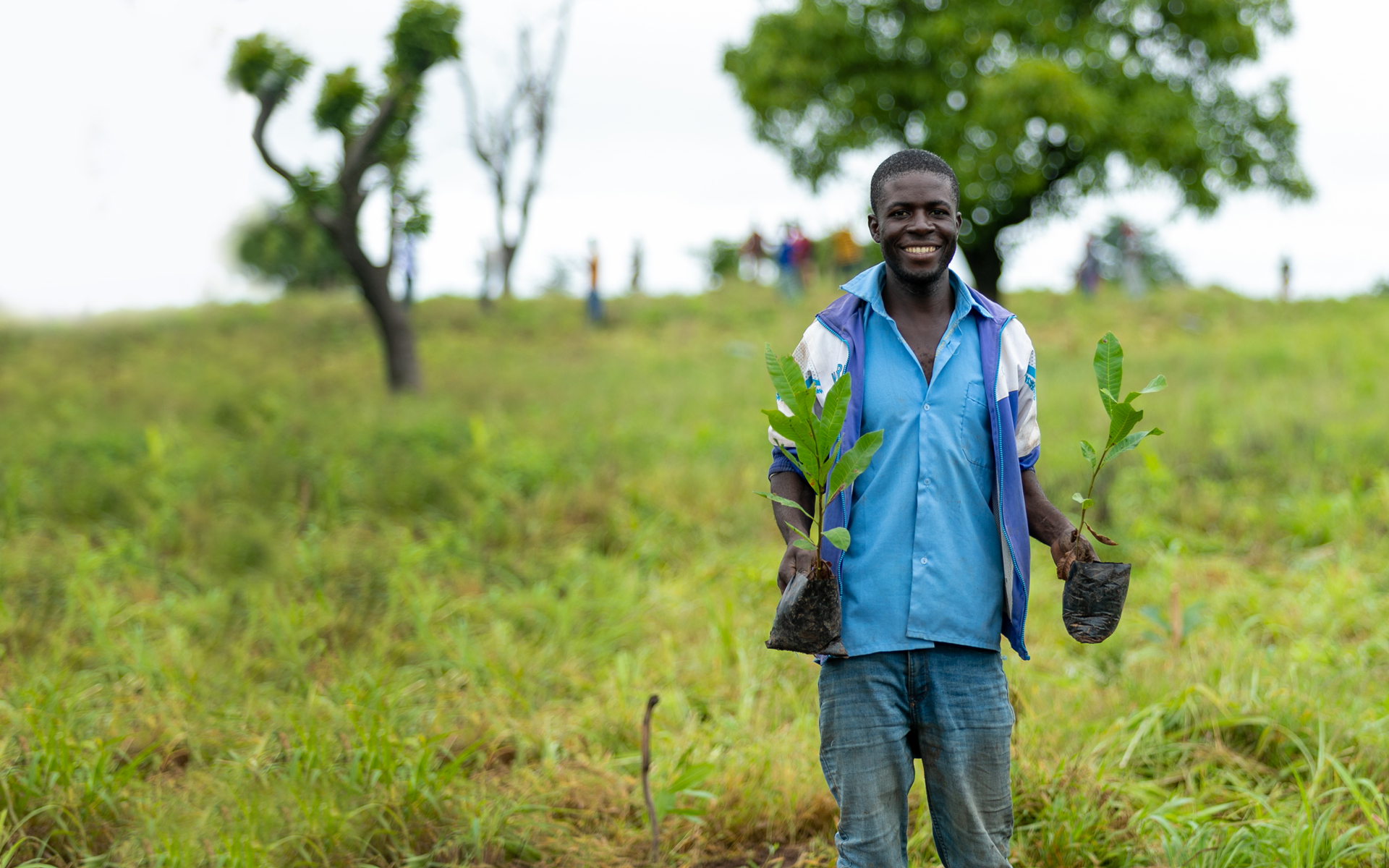 Francis, a man we are working with in Ghana, holding a tree sapling in each hand which he will plant in the community.