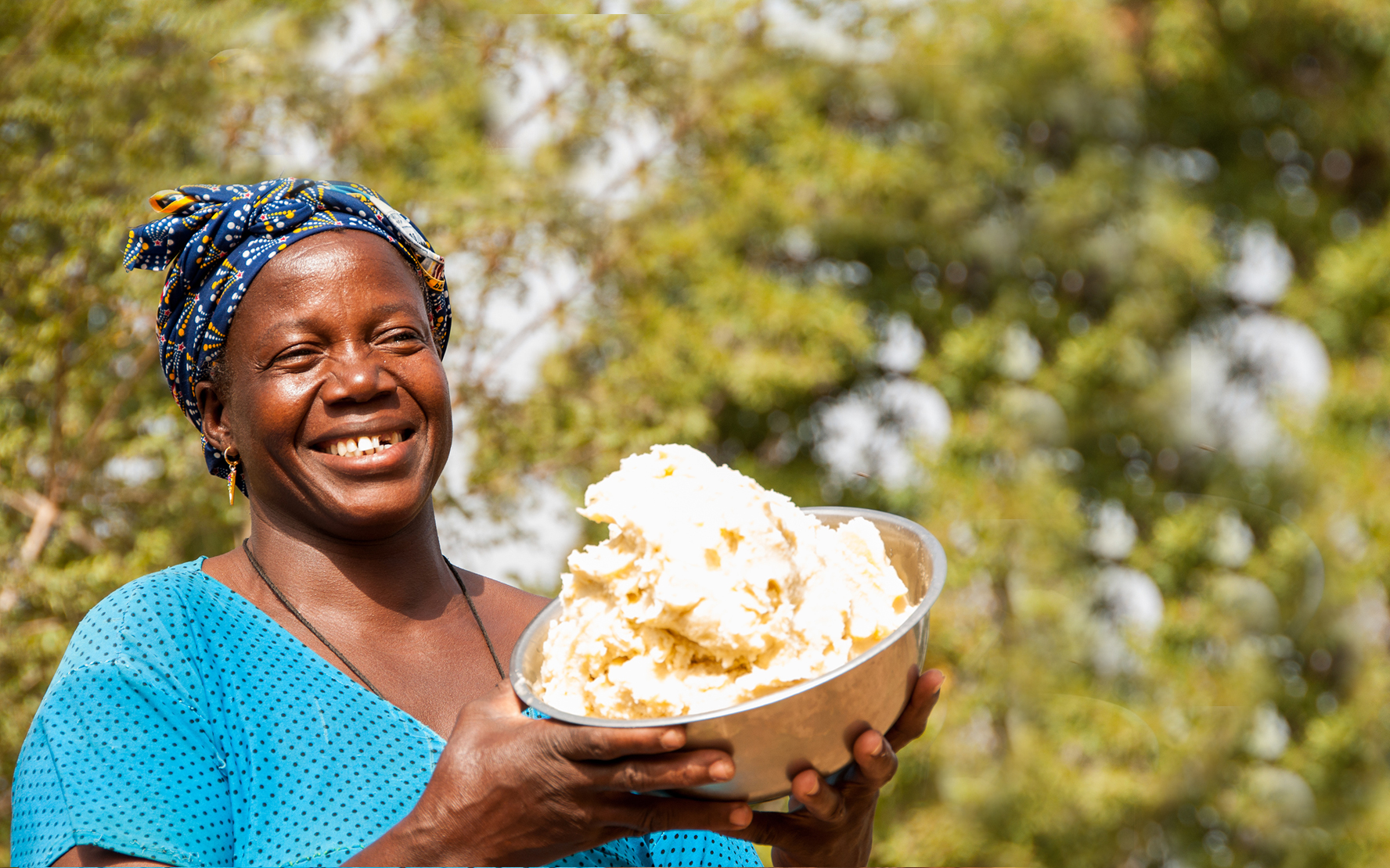 Bernadette, a member of a shea enterprise group set up through a Tree Aid project, holding shea butter and smiling.