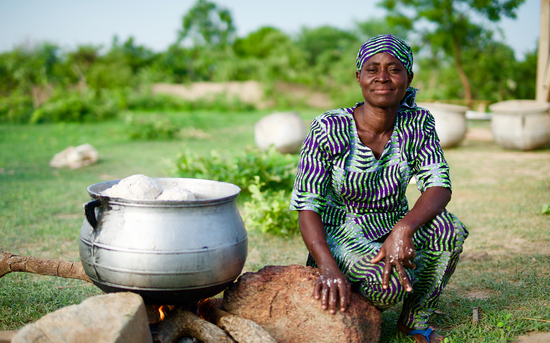 Awa, a women in a shea butter enterprise group, smiling while she boils shea butter.