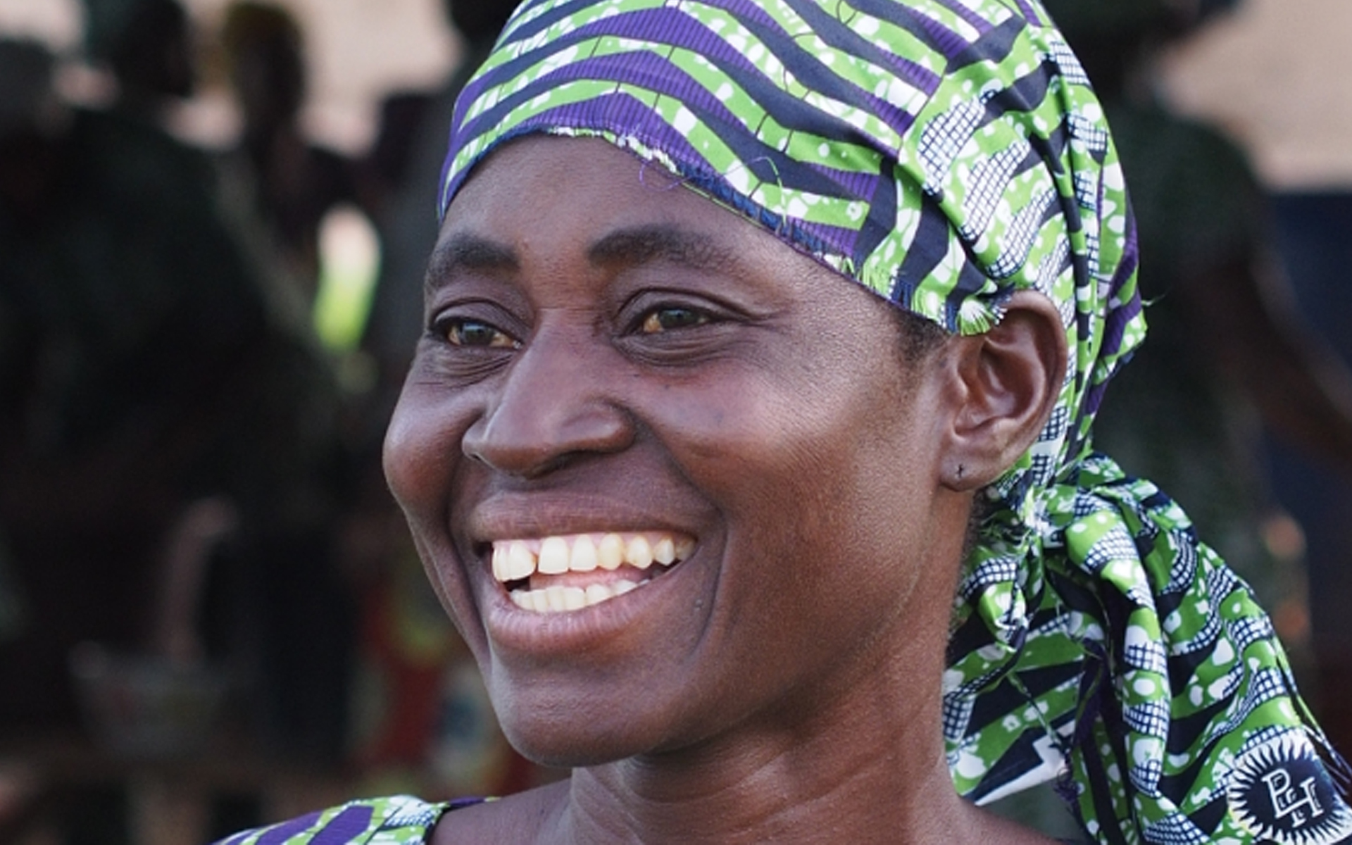 Close up of Awa, a woman in a shea enterprise group, smiling.